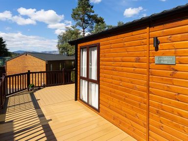 Wooden deck with railing outside a cabin named Lancashire Rose in Ambleside