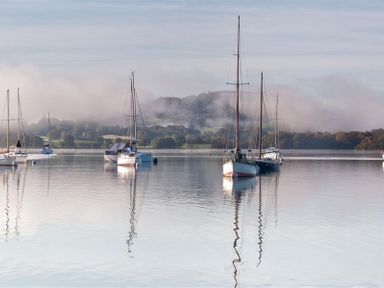 A lake with several sailboats anchored and hills in the background at Lancashire Rose in Ambleside