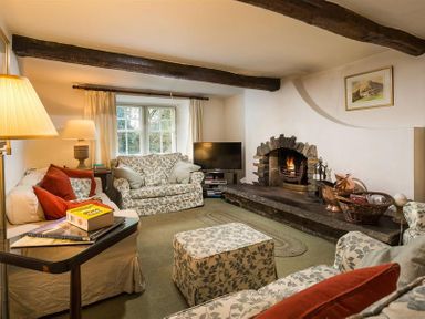 A living room with sofas and an armchair around a fireplace at High Cleabarrow in Windermere