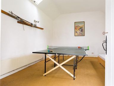 A room with a ping pong table and vintage skis mounted on the wall at High Cleabarrow in Windermere