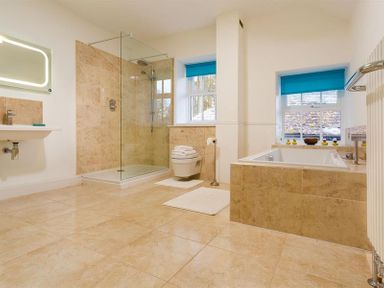 A bathroom with a shower enclosure toilet bathtub and sink with windows at High Cleabarrow in Windermere