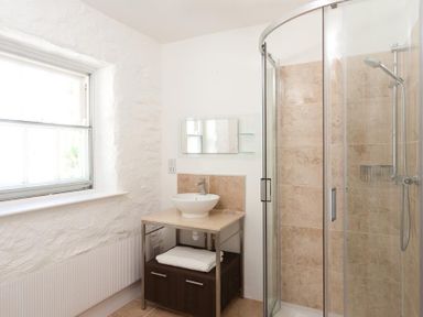 A bathroom with a window a sink on a wooden vanity and a glass shower enclosure at High Cleabarrow in Windermere