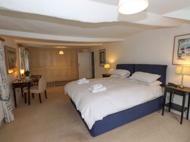 A bedroom with a double bed side tables lamps a desk chair and built in wardrobes at High Cleabarrow in Windermere