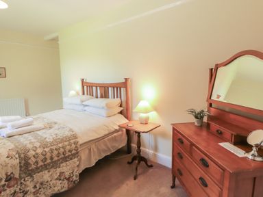 A bedroom with a bed and dresser at Hawkshead Hall in Hawkshead