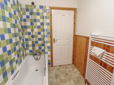 A bathroom with a bathtub and tiled walls at Hawkshead Hall in Hawkshead