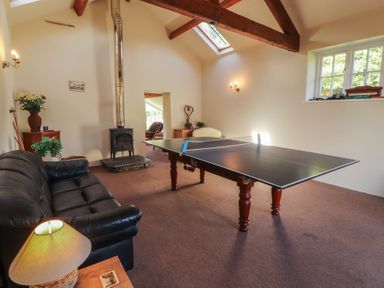 A recreation room with a ping pong table and sofa at Hawkshead Hall in Hawkshead