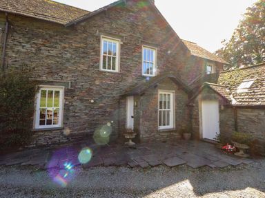 An exterior view of a stone house with a pathway and flowers at Hawkshead Hall in Hawkshead