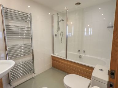 A bathroom with a bathtub shower combination towel rack toilet and sink at Idle Mill 2 in Ambleside