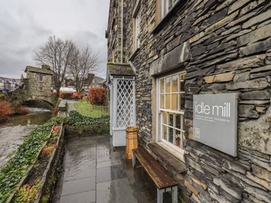 A stone building with a sign idle mill next to a river and stone bridge at Idle Mill 2 in Ambleside