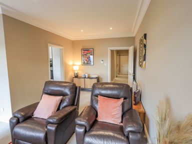 A living room with two leather armchairs and a sideboard with a lamp and artwork at Waterhead Retreat in Ambleside