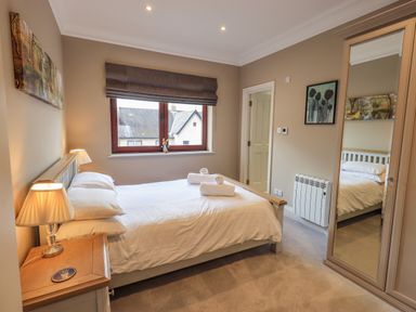 A bedroom with a double bed side tables lamps a window and a mirrored wardrobe at Waterhead Retreat Ambleside