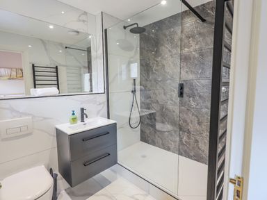 A bathroom with a glass-enclosed shower and a black vanity with a sink at Waterhead Retreat in Ambleside