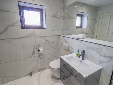 A bathroom with a toilet sink mirror and a window at Waterhead Retreat in Ambleside