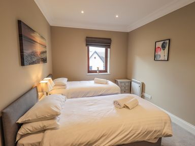 A bedroom with two single beds bedside table window and two wall pictures at Waterhead Retreat in Ambleside