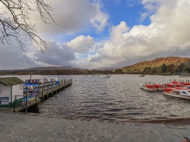 A lake with boats docked at piers and hills in the background at Waterhead Retreat in Ambleside