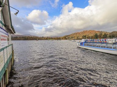 A lake with boats and a docked boat next to a building with a sign at Waterhead Retreat in Ambleside