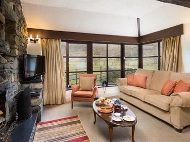 A living room with a sofa armchair coffee table and window at Thirlmere Cottage in Grasmere