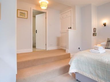 A bedroom with a bed and steps leading to a doorway at Thirlmere Cottage in Grasmere