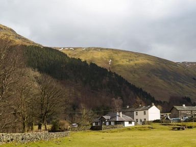 A rural area with houses trees and hills in the background at Thirlmere Cottage in Grasmere