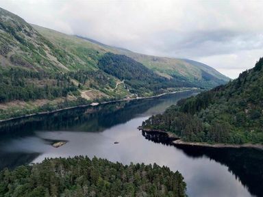 A lake surrounded by hills and dense forests under a cloudy sky at Thirlmere Cottage in Grasmere