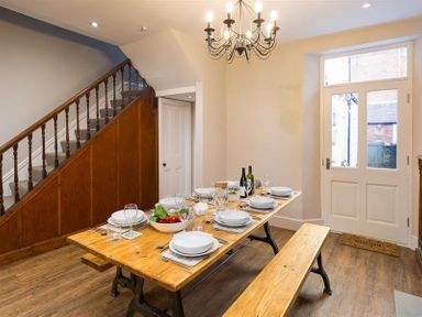 A dining room with a wooden table set for six and a wooden bench near stairs and a door at Thirty Blencathra Street Keswick