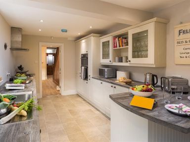 A kitchen with white cabinets a fruit bowl and kitchen appliances at Thirty Blencathra Street in Keswick