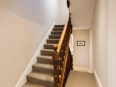 A carpeted staircase with wooden handrails and beige walls at Thirty Blencathra Street in Keswick