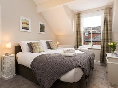 A bedroom with a double bed and plaid curtains at Thirty Blencathra Street in Keswick