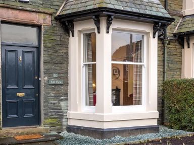A front view of a house entrance with a dark blue door and a bay window next to it at Thirty Blencathra Street Keswick
