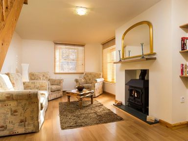 A living room with armchairs a coffee table and a fireplace at Agathi in Keswick