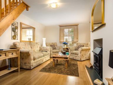 A sitting room with patterned sofas a wooden coffee table a small rug and a fireplace at Agathi in Keswick
