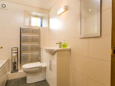 A bathroom with a toilet sink with cabinet mirror and heated towel rail at Agathi in Keswick