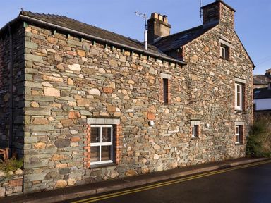 An exterior view of a stone house with multiple windows and chimneys at Agathi in Keswick