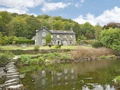 A stone house with a garden near a river and stepping stones at Stepping Stones House in Ambleside