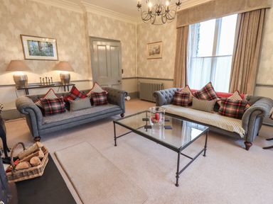 A living room with two grey sofas and a glass coffee table at Stepping Stones House in Ambleside