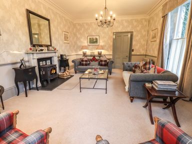 A living room with gray sofas and plaid cushions a fireplace and armchairs at Stepping Stones House in Ambleside