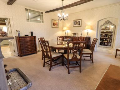 A dining room with a round table and six chairs wooden furniture and a large mirror in Stepping Stones House Ambleside