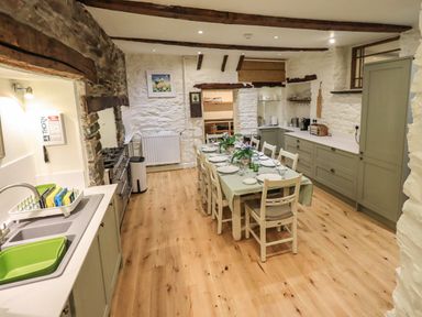 A kitchen with wooden beams a dining table set with plates and chairs at Stepping Stones House Ambleside
