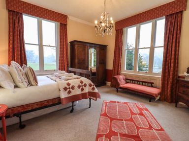 A bedroom with a bed and a wooden wardrobe and a red chaise lounge at Stepping Stones House Ambleside