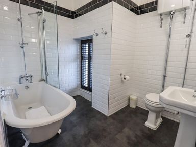 A bathroom with a bathtub shower toilet and sink at Stepping Stones House in Ambleside