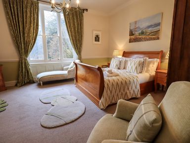 A bedroom with a wooden bed and chaise lounge by the window at Stepping Stones House in Ambleside