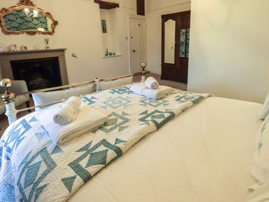 A bedroom with a bed with folded towels a fireplace and a wooden wardrobe at Stepping Stones House in Ambleside