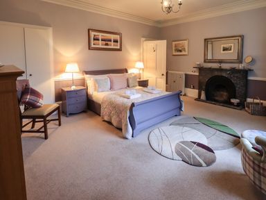 A bedroom with a bed two bedside tables a chair and a fireplace at Stepping Stones House in Ambleside