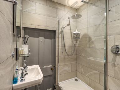 A bathroom with a shower enclosure and a small sink at Stepping Stones House in Ambleside