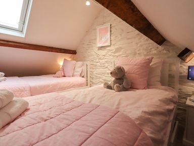 A bedroom with two beds pink bedding stuffed animals and a skylight at Stepping Stones House in Ambleside