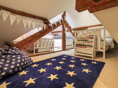 A children's bedroom with two white beds a blue star patterned rug a bean bag and a book rack at Stepping Stones House in Ambleside