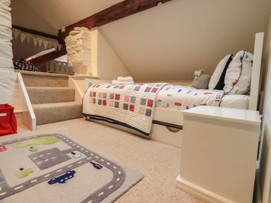A child's bedroom with a low bed beside stairs and a road-themed rug at Stepping Stones House Ambleside