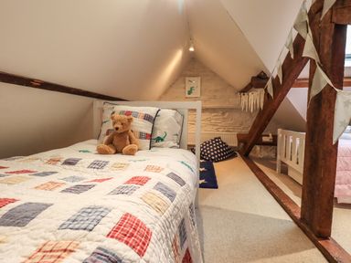 A child's bedroom with two single beds a teddy bear on one bed and wooden beams at Stepping Stones House Ambleside