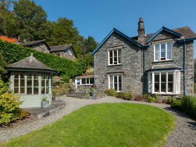 Stone house with blue trim garden gazebo gravel path and green lawn at Stepping Stones House in Ambleside