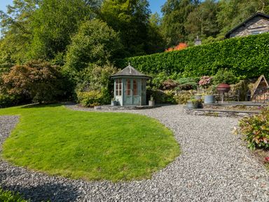 A garden with a green gazebo stone paths plants and a seating area at Stepping Stones House in Ambleside